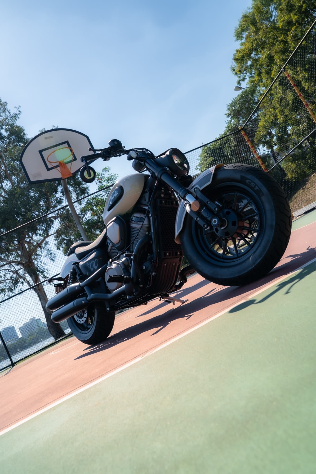 Custom bobber motorcycle — basketball court in daylight
